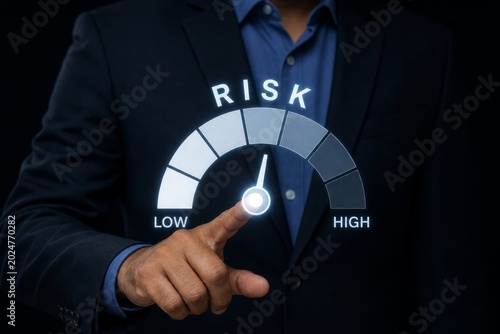 Businessman's finger points to a digital gauge indicating low risk on a dark background, representing risk assessment.