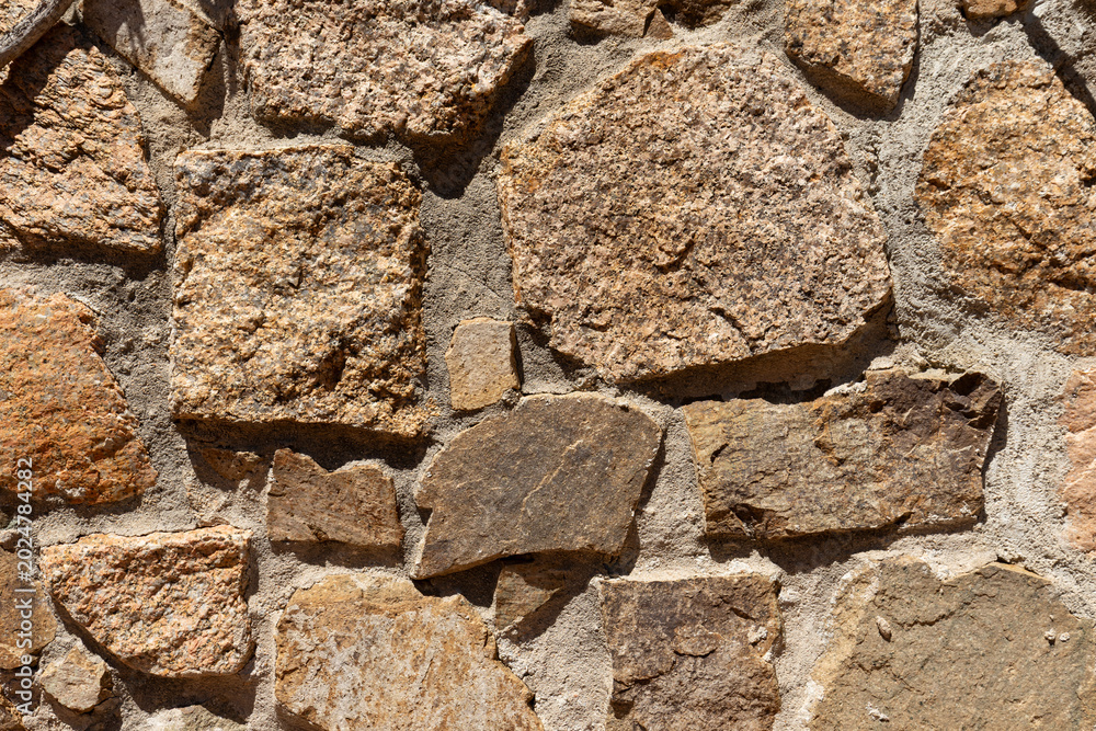 Fototapeta premium Close-up of a rustic stone wall with irregular shapes and natural textures, modern wallpaper, background or web banner
