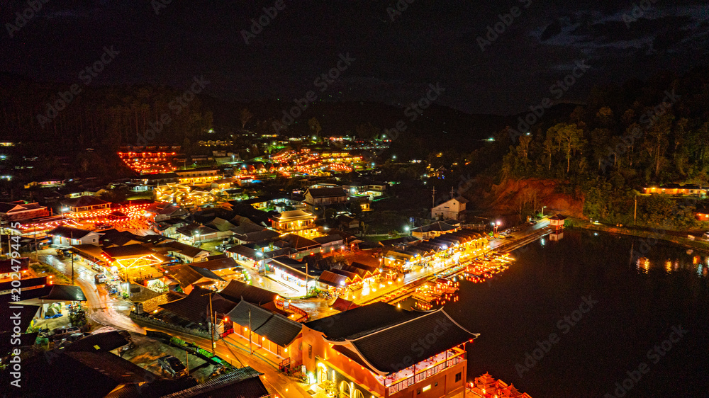 Fototapeta premium At dusk the reflections of the lights from the village the lake in Chinese-style structures with colorful lights lined the waterfront. Ban Rak Thai is a popular tourist attraction in Mae Hong Son