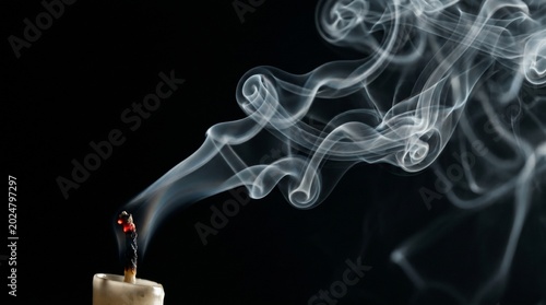 Foto Wispy trails of gray smoke rise gracefully from the extinguished wick of a white