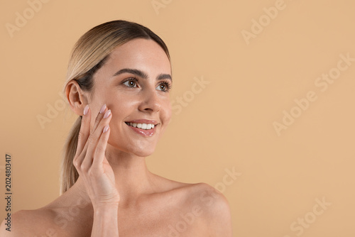 Foto Smiling young caucasian woman with radiant healthy skin touching cheek in beauty