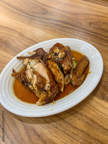 Photography Popular Hainanese fried chicken served in Bukit Bintang Kuala Lumpur, featuring crispy golden texture, rich savory sauce, and authentic Malaysian culinary atmosphere
