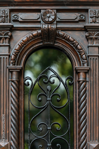 Cuadro en lienzo Carved wooden door with arched wrought iron window, classical ornaments detail,