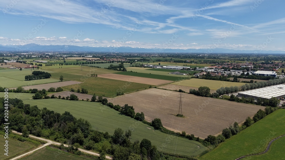 Naklejka premium Italian Countryside Landscape: An expansive aerial view showcases the patchwork of cultivated fields and verdant pastures typical of the Italian countryside.