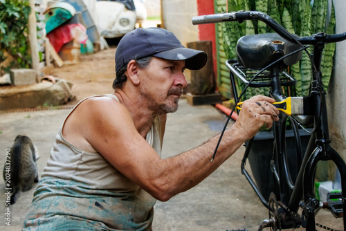 Foto Focused middle aged man painting and restoring a bicycle frame outdoors in a modest residential backyard