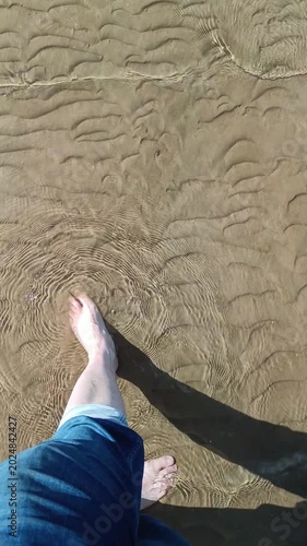 Bare Feet Walking in Shallow Water With Sand Ripples 