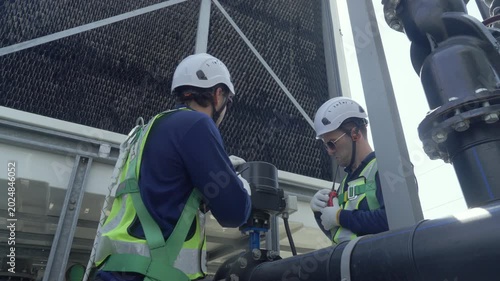 Engineer maintenance hvac cooling tower technician repair industrial pipe valve under review, crew inspect heat exchange unit on site with safety helmet glove, service fan motor pump, harness crew