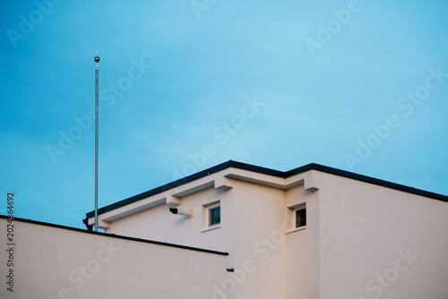 Modern apartment exterior with lightning rod and small windows, minimalist urban architecture composition