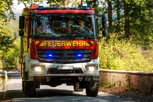 Tableau sur toile German LF 10 fire truck driving on road with blue emergency lights