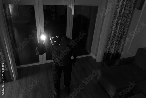 Quadro em tela Male thief entering home through doorway during nighttime, involved in covert bu