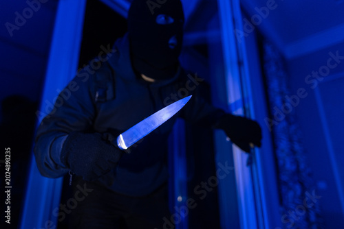 Schilderij op canvas Armed burglar with knife moving carefully to private property at night, involved