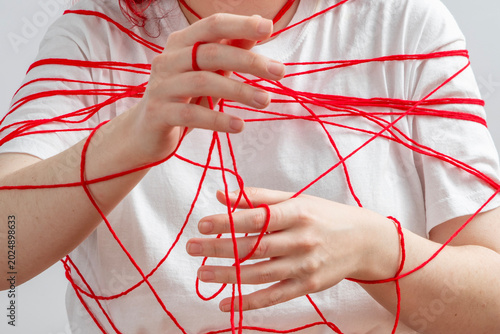 Bild auf Leinwand Young woman wrapped in red lines symbolizing imposed social rules, pressure and stereotypes, personal boundaries and conflict avoidance, fear of confrontation and self expression
