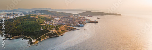 Aerial view of industrial harbor and ship recycling area with polluted sea surface near coastline. Marine industry and environmental impact