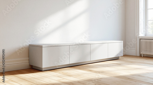 Minimal white sideboard stands against a bright wall in a sunlit room with wooden floor and window.