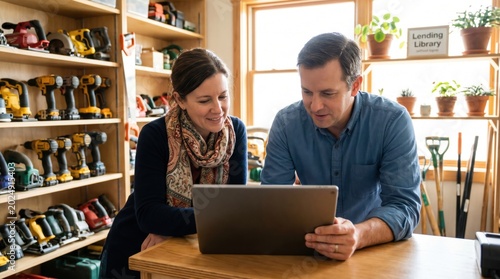 Man and woman browsing tool inventory on laptop together at community lending library