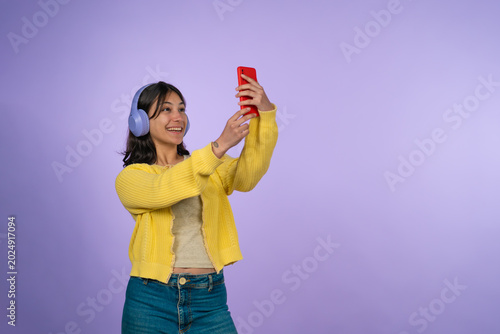 Young woman taking selfie with smartphone and headphones