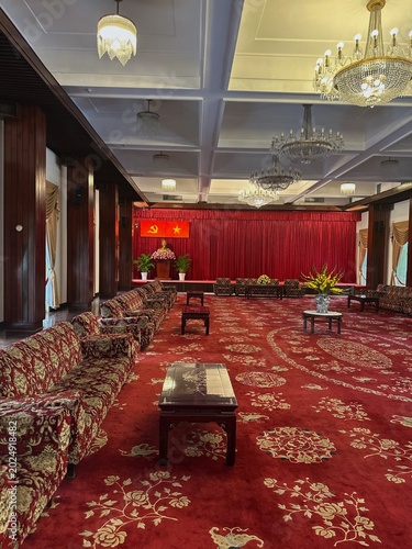Foto An opulent ceremonial hall featuring a large patterned red carpet, crystal chandeliers, and classic wooden paneling