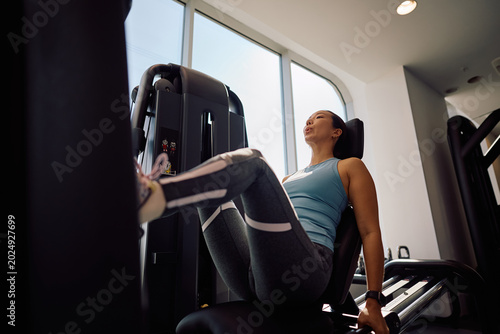 Foto Below view of sportswoman exercising on leg press machine during sports training in gym