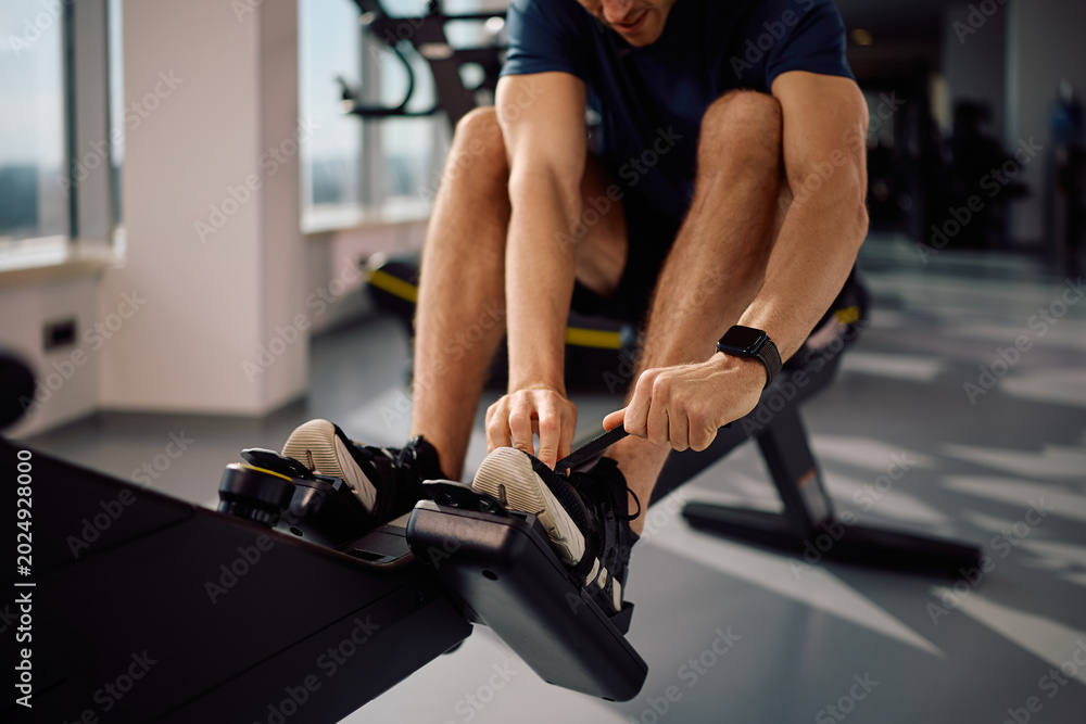 Fototapeta premium Close up of athlete preparing for exercising on rowing machine in gym.