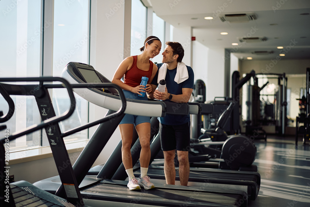 Obraz premium Happy athletic couple having fun during water break in gym.