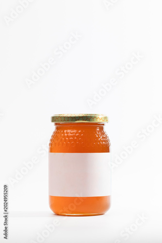 Clear glass jar holds golden natural wildflower honey