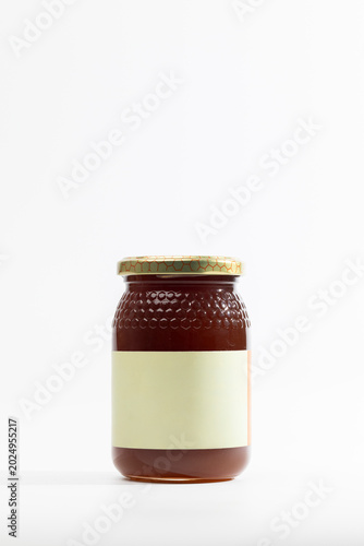 Glass jar holds amber natural forest honey