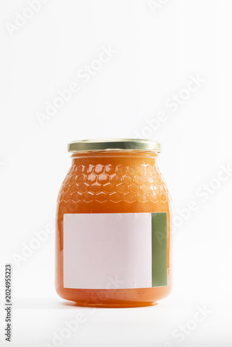 Orange jam in glass jar of natural thyme honey with textured surface