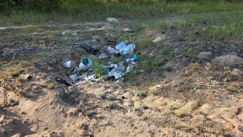 Εκτύπωση καμβά Pile of mixed plastic and paper garbage dumped in a sandy pit surrounded by gree
