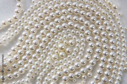 Fotografie Beautiful necklace and single pearls on white satin background for background or