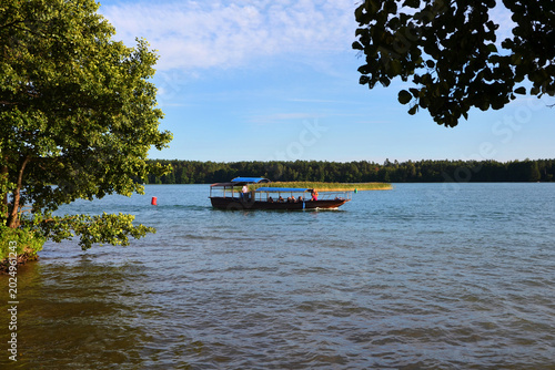 Fotografia Small tourist pleasure boat cruising on a scenic lake