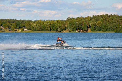 Man riding a jet ski making a turn on a scenic summer lake. Active water sports