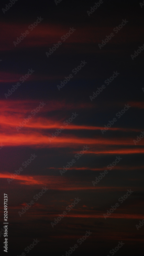 Fototapeta premium Dramatic red and dark clouds during sunset or sunrise in a vertical format