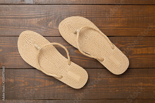 Pair of burlap flip-flops on wooden background, top view