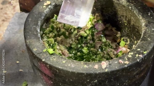 Closeup of Grinding Chilis with a Mortar and Pestle to Make Thai Green Curry Paste