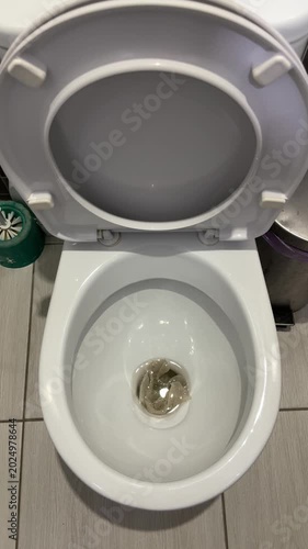 White porcelain toilet bowl stained with urine, overhead view in tiled bathroom showing toilet brush, gray plumbing pipe, used