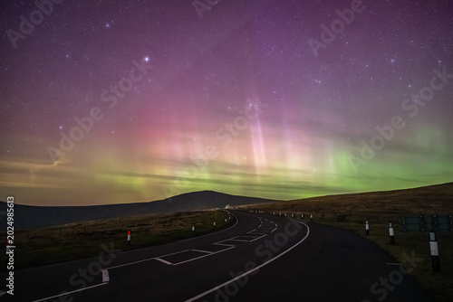 A panoramic night landscape of the Isle of Man’s Mountain Road winding through the uplands towards the distant peak of Snaefell mountain.