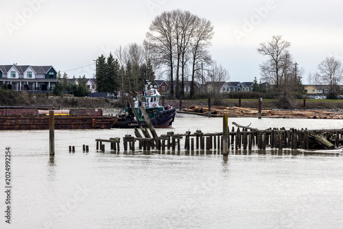 Canvas Print Tugboat And Log Barge On Fraser River Waterfront With Houses And Old Pilings, Ne