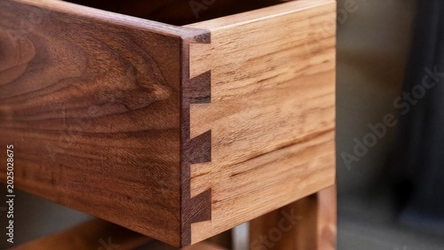 dovetail. Close-up of a handcrafted wooden dovetail joint, intricate grain patterns. safety posters, maintenance manuals, designed for precision metalworking and fabrication facilities.