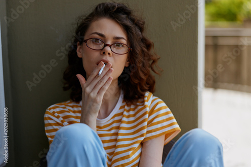 Foto Woman smoking, casual lifestyle in a homey setting, portrait with glasses, striped shirt, relaxed mood, candid moment of everyday life, warm daylight and thoughtful expression
