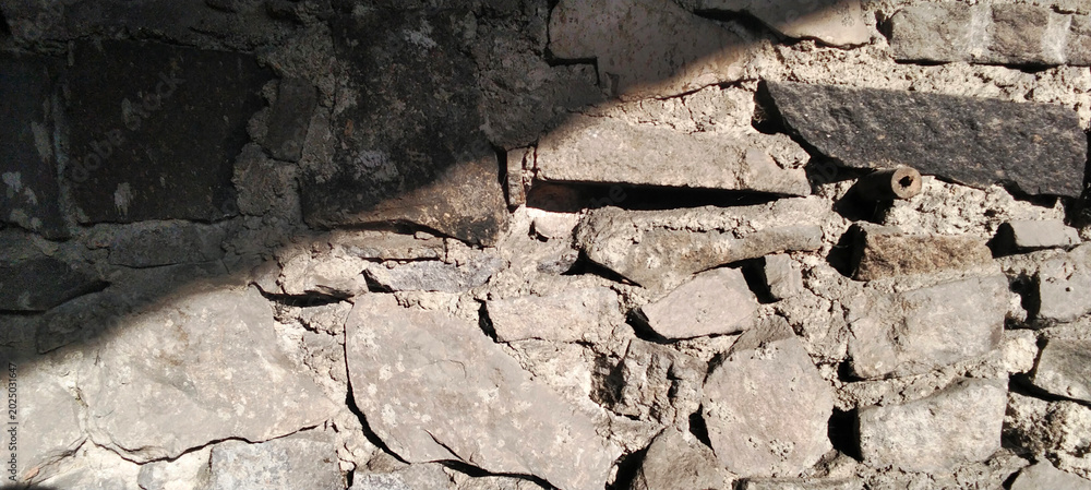 Fototapeta premium Ancient natural stone wall texture with dramatic lighting.