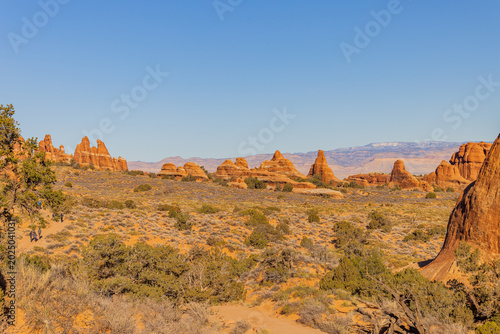 Hikers walk through the stunning red rock formations at Arches National Park.