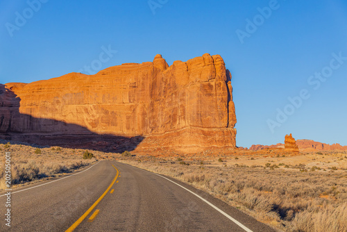 Принти на полотні Asphalt road leads toward the massive red sandstone rock formation