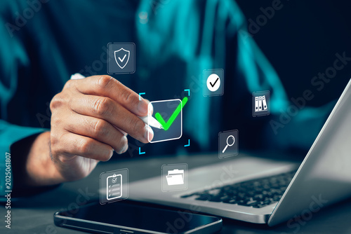 Evaluation survey by businessman using digital check mark for approval, quality assessment document and business checklist, professional person with laptop stylus for corporate office work