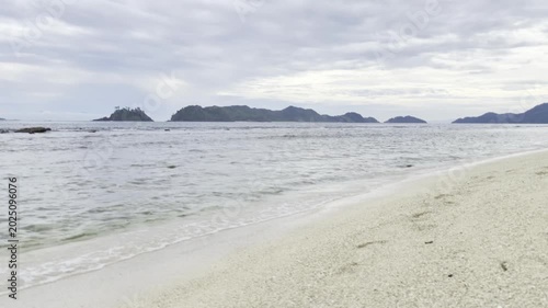 Serene Coastal Landscape with Distant Islands and Calm Ocean Waves on a Cloudy Day.