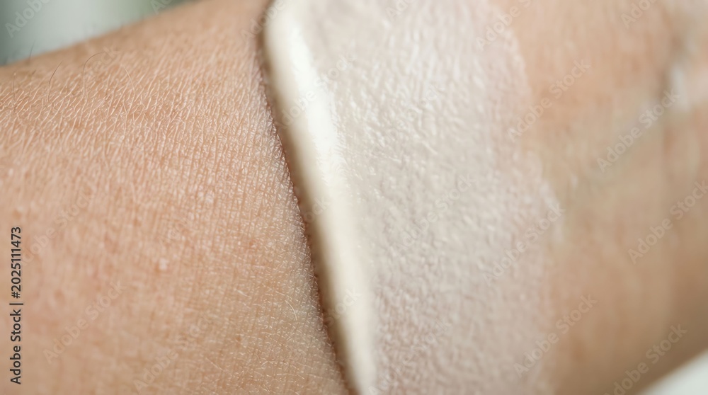 Fototapeta premium Close-up of a person applying a white cosmetic or skincare product on skin.