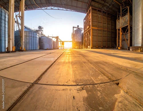 Sunlit Industrial Grain Storage Facility with Empty Concrete Floor at Sunrise
