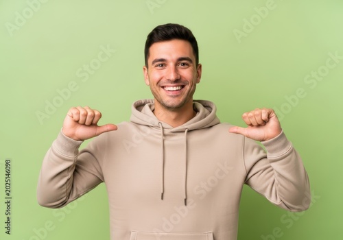 Young man wearing beige hoodie pointing at himself