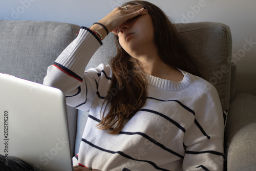 Foto Young woman feeling overwhelmed and stressed from work, covering her face while