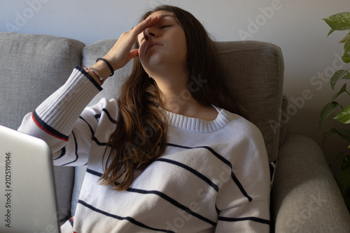 Young woman working remotely from home feeling stressed , experiencing tiredness and displeasure