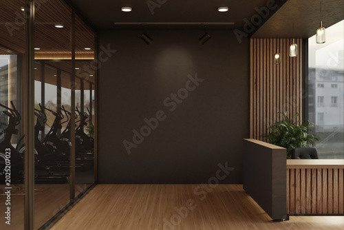 Black wall between glass door of exercise room and reception counter in a modern luxury fitness gym.